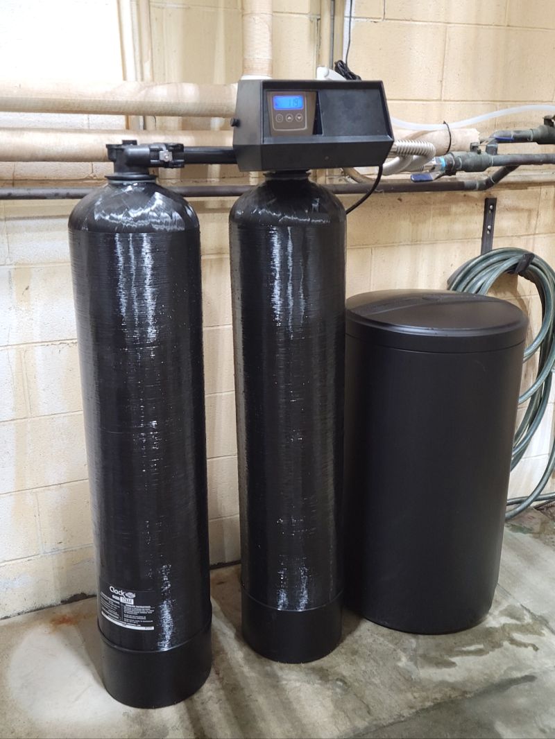 Twin FRP commercial water softener tanks with a Fleck control valve and brine tank, a Hoffman Soft Water installation
